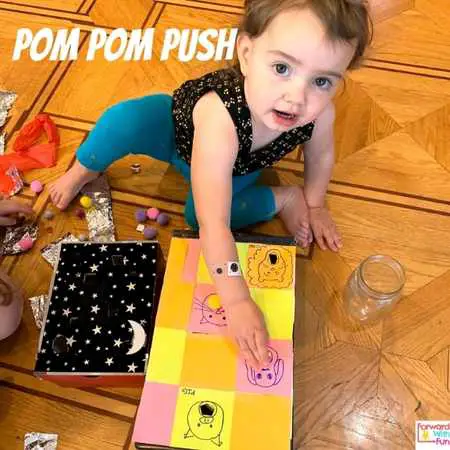 counting pom poms by pushing them through the shoebox