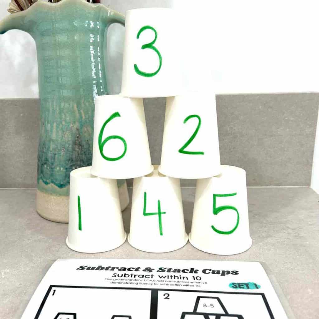 level 1 subtraction fact fluency example with 6 paper cups stacked in a pyramid based on the challenge of subtraction problems set forth below it