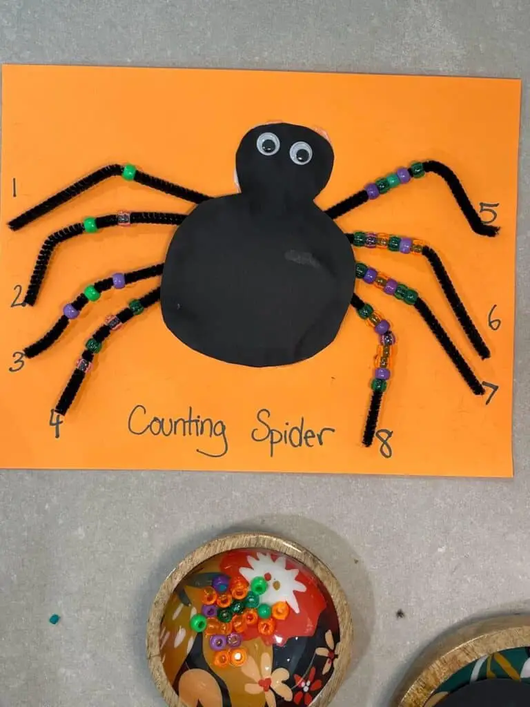 kids practice one to one correspondence by placing beads on the legs of a spider, matching the quantity to the numeral